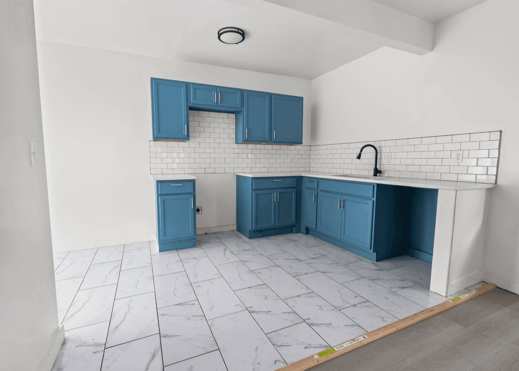 Turnkey Rental Property Case Study Kansas City Gallery Image 4 - Cashflow Rentals | USA Property Investments Blue kitchen cabinets and white subway tile backsplash in an unfinished kitchen under construction.